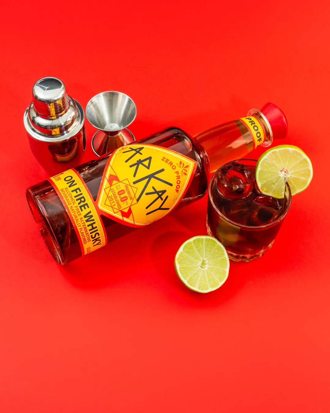 ARKAY On Fire whisky alternative with lime and a zero-proof mocktail on a red background