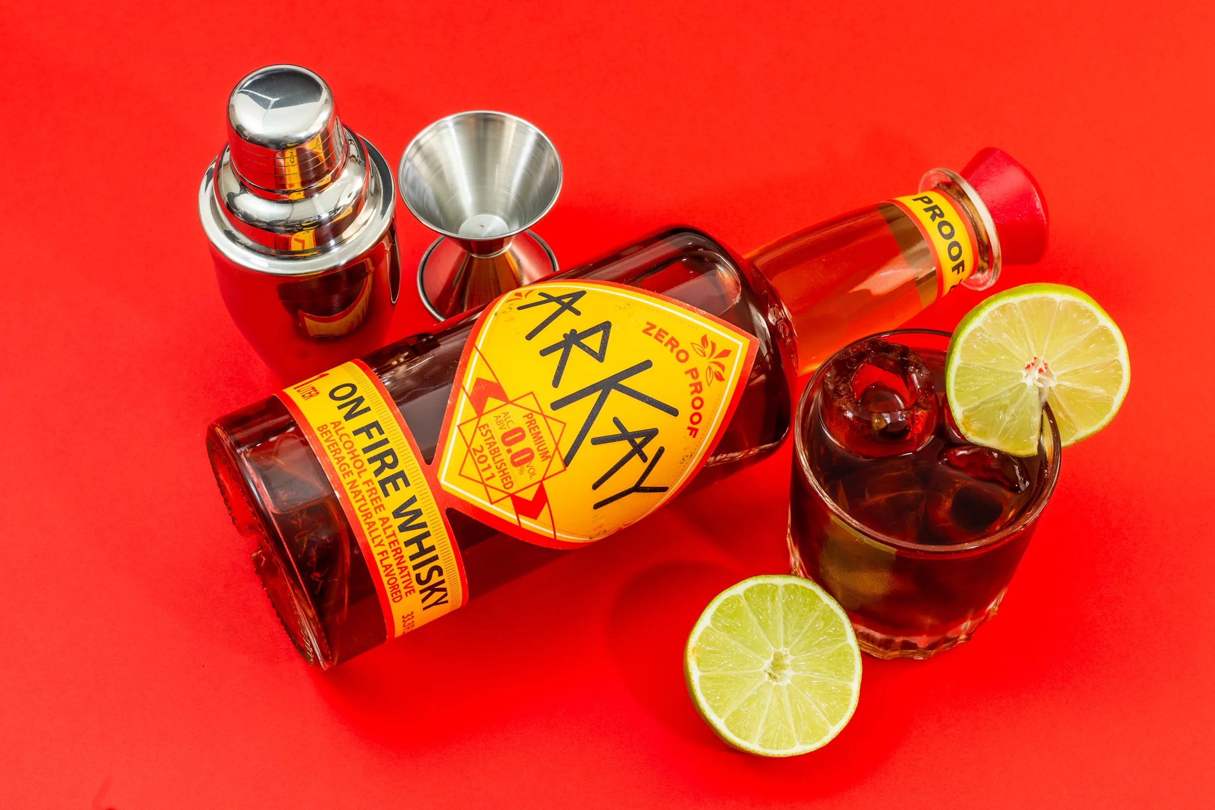 ARKAY On Fire whisky alternative with lime and a zero-proof mocktail on a red background